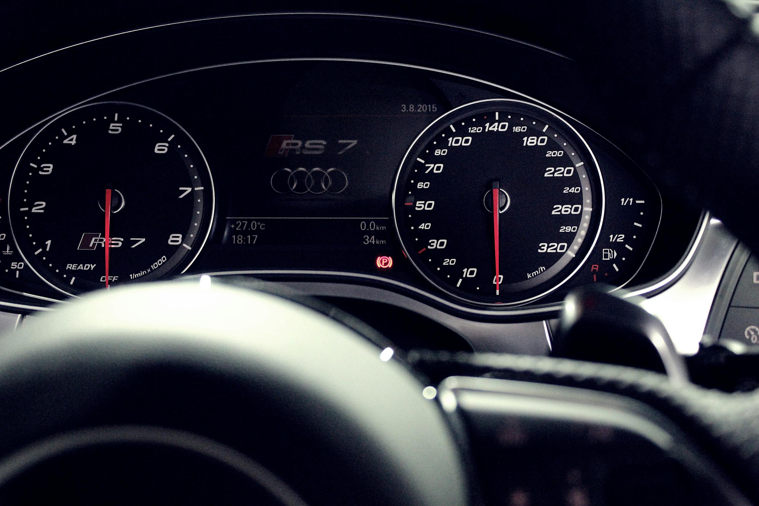 Close-up view of a luxury car dashboard featuring speedometer and gauges at night.