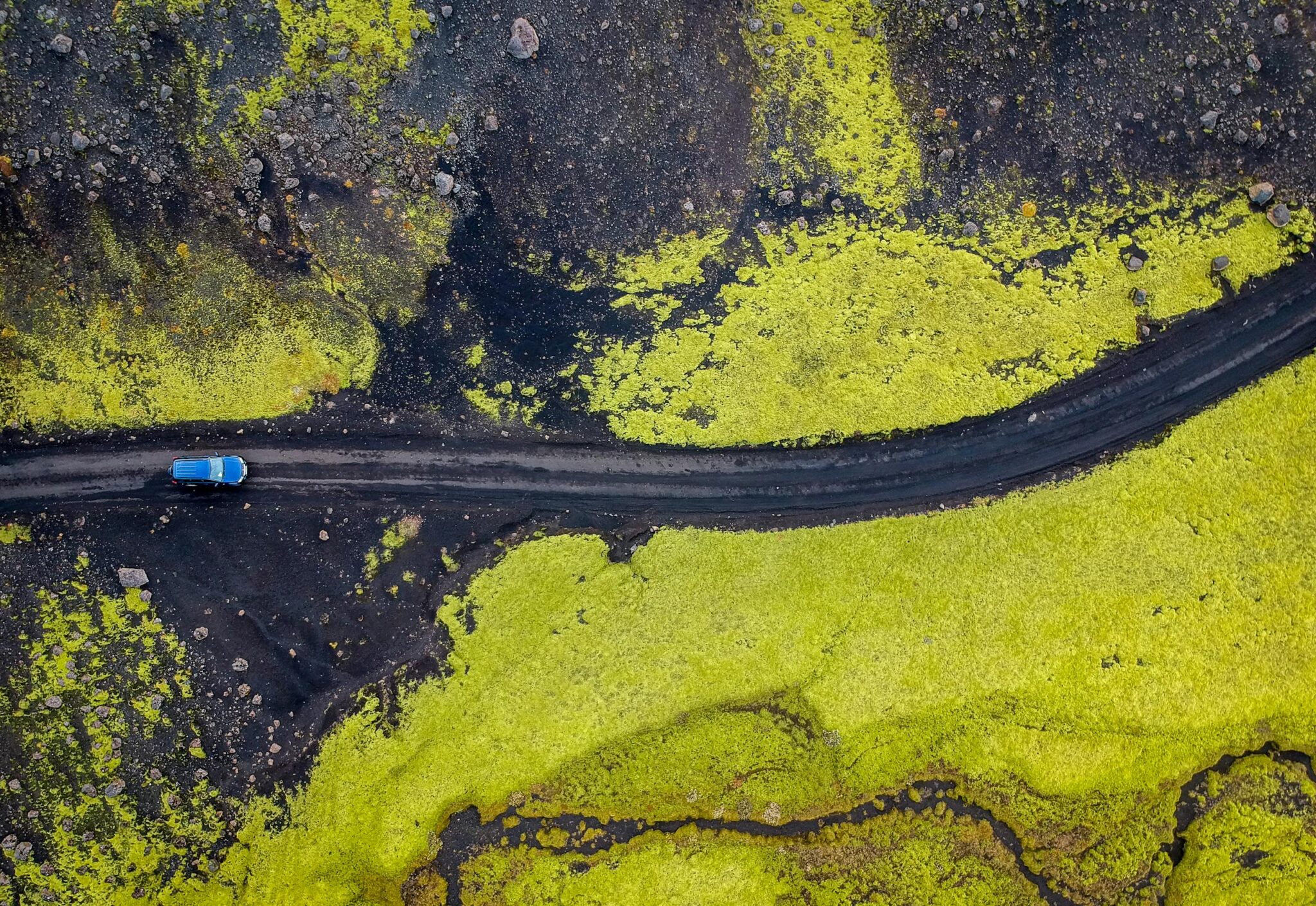 A stunning aerial view of a car traversing a scenic road in the Southern Region of Iceland.