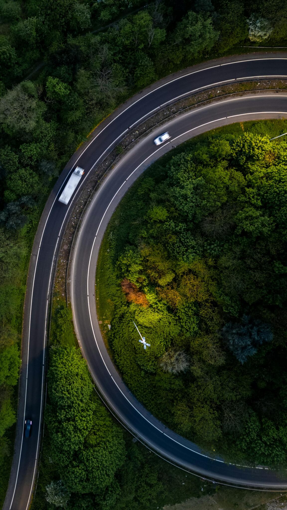 Stunning aerial view of a curved road surrounded by lush greenery in Leeds, United Kingdom.